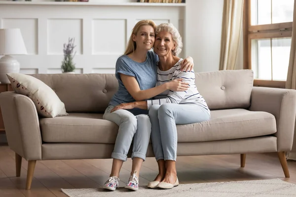 Retrato de una joven rubia sonriente abrazando a su anciana madre . — Foto de Stock