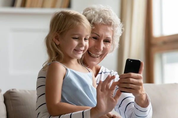 Volwassen vrouw tonen grappige mobiele apps naar klein kind meisje. — Stockfoto