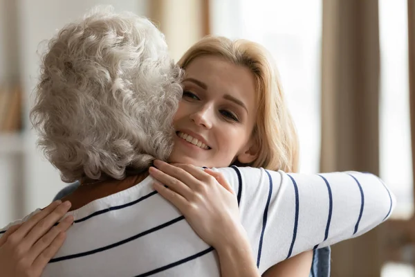 Mujer de mediana edad abrazando sonriente adulto atractiva hija . — Foto de Stock