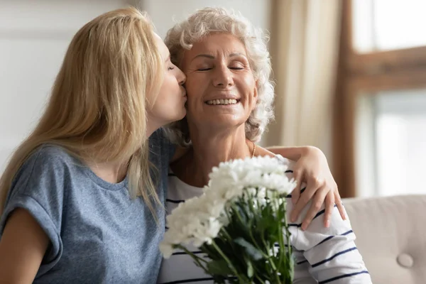 Grown up daughter kissing cheek of smiling older senior mother. — Stock Photo, Image