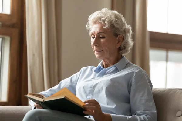 Peaceful middle aged woman reading paper book bestseller at home. — Stock Photo, Image