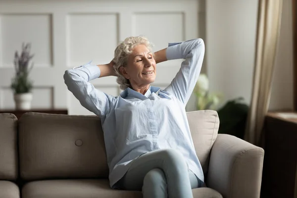 Pacifico de mediana edad tranquila mujer relajante en el sofá acogedor . — Foto de Stock