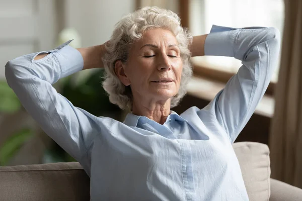 Friedliche ältere Oma entspannt sich mit geschlossenen Augen auf der Couch. — Stockfoto
