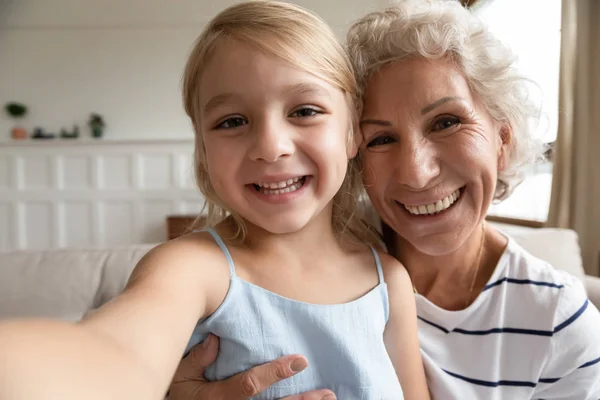 Kleine Vorschulenkelin nimmt lustiges Video mit aufgeregter älterer Großmutter auf. — Stockfoto