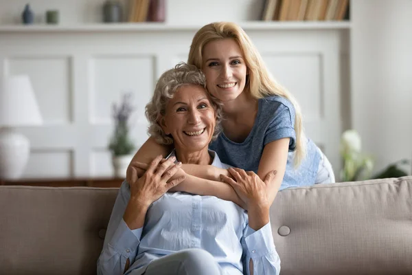 Gelukkige aanhankelijke jonge vrouw knuffelen glimlachen volwassen gepensioneerde moeder. — Stockfoto