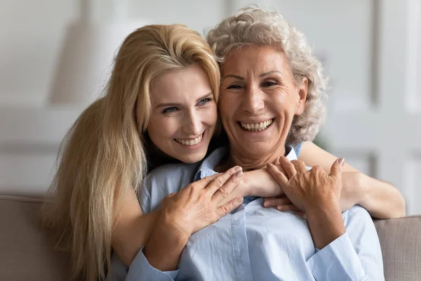 Atractiva sonriente joven rubia abrazando mayor agradable mami . — Foto de Stock