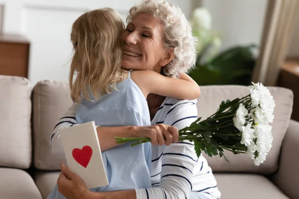 Liten barn flicka gratulera glad äldre senior mormor med födelsedag. — Stockfoto