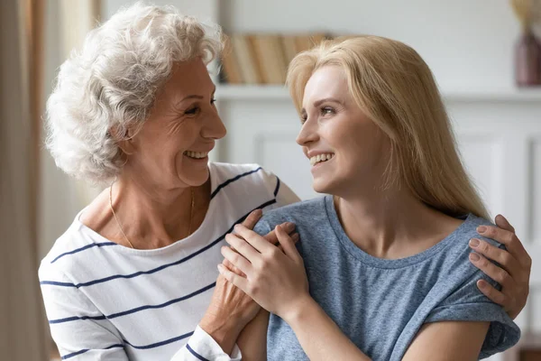 Pleasant happy middle aged mother embracing smiling grownup daughter. — Stock Photo, Image