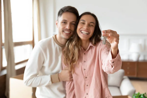 Happy young couple show home keys relocating to new house — Stock Photo, Image