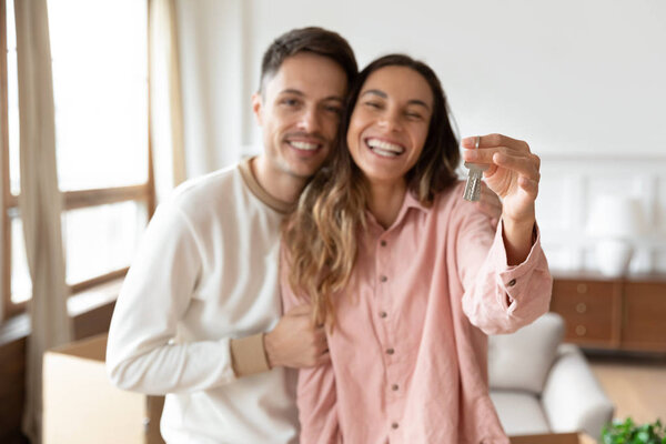 Happy young couple show home keys relocating to new house