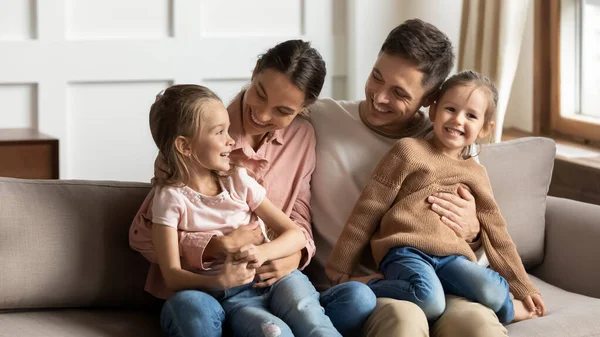Amare la giovane famiglia con i bambini rilassarsi in soggiorno — Foto Stock