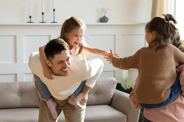 Überglückliche kleine Mädchen huckepack Eltern spielen zu Hause — Stockfoto