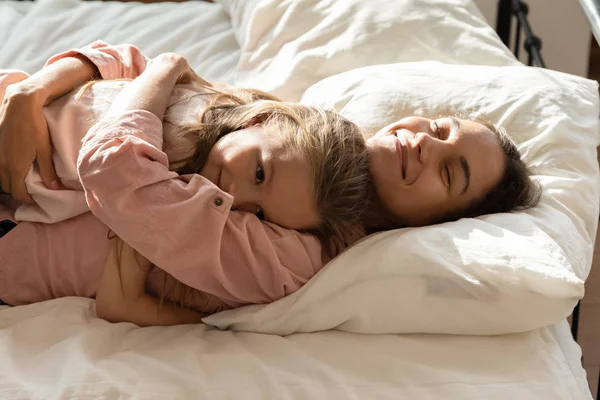 Cariñosa mamá abrazo relajante en cama con poco hija —  Fotos de Stock