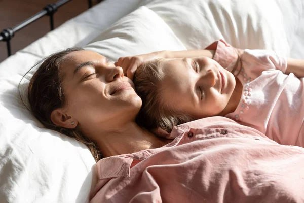 Feliz mamá relajándose durmiendo con su hija pequeña en la cama —  Fotos de Stock