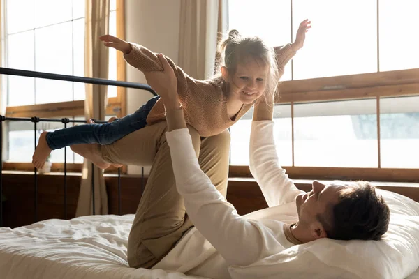 Älskade pappa leker med upphetsad liten dotter i sovrummet — Stockfoto