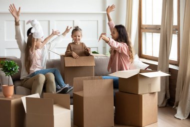 Neşeli genç ebeveynler taşınma gününde küçük çocuklarla oynuyorlar.