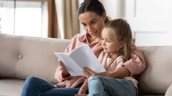 Madre cariñosa relajarse leyendo libro con su hija pequeña — Foto de Stock