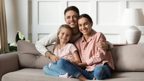 Porträt einer glücklichen jungen Familie mit Tochter, die es sich auf der Couch gemütlich macht — Stockfoto