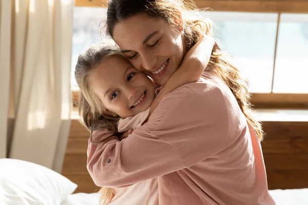 Feliz joven mamá y su hijita abrazándose en casa —  Fotos de Stock