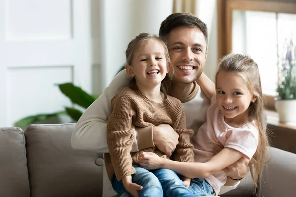 Happy dad cuddle little daughters relaxing together at home — Stock Photo, Image
