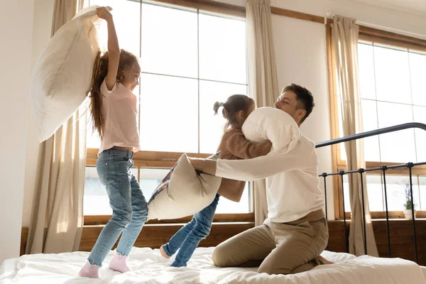 Überglücklicher junger Vater kämpft mit kleinen Töchtern im Schlafzimmer — Stockfoto