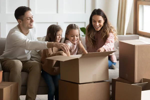 Famiglia eccitata con bambini piccoli disfare le valigie in una nuova casa — Foto Stock