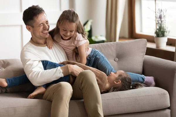Dolblij jonge vader spelen met dochters in de woonkamer — Stockfoto