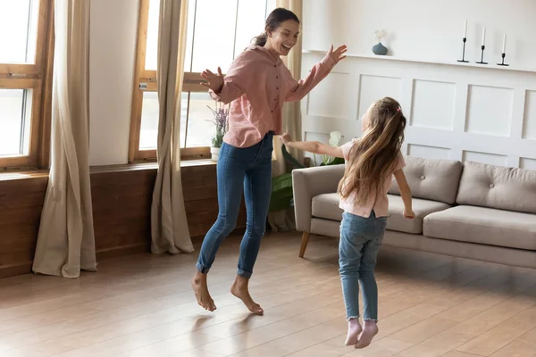 Overgelukkig jong mam en kleine dochter dansen in de woonkamer — Stockfoto