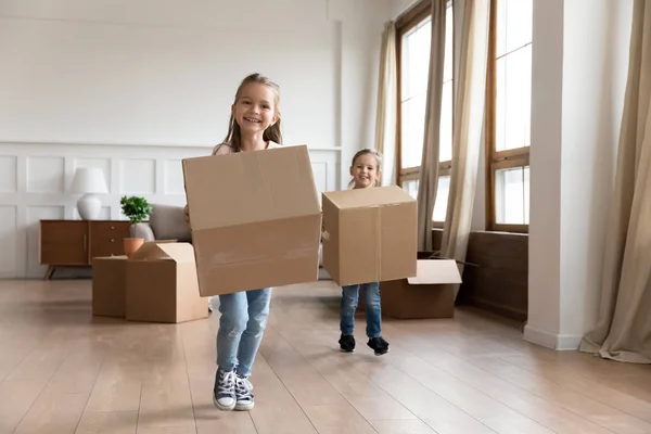 Meninas pequenas felizes carregam pacotes no dia em movimento em casa — Fotografia de Stock