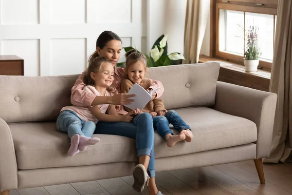 Milující mladá maminka čtení kniha s malými dcerami — Stock fotografie