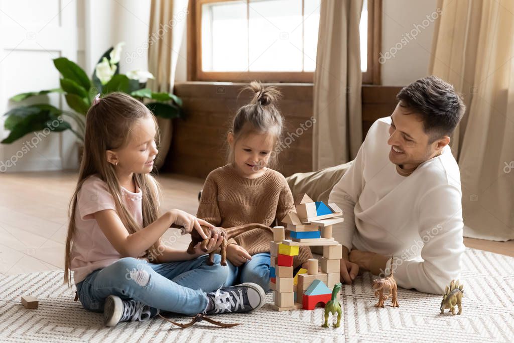 Loving father play with cute little daughters at home