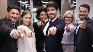 Farklı yaşlarda mutlu çok ırklı iş adamları kamerayı işaret ediyor..