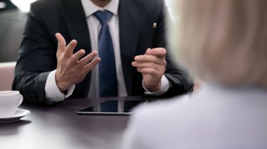 İş adamının elinde kalem tutarak ortaklara önerileri açıklıyor..