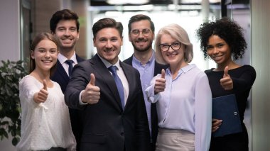 Gülümseyen karışık ırk farklı yaşlarda takım arkadaşları başparmak işareti gösteriyor..