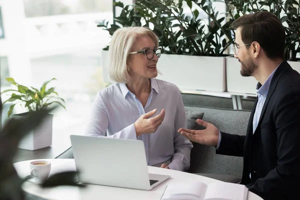 Feliz líder mayor comunicándose con su compañero sonriente, discutiendo el proyecto . — Foto de Stock