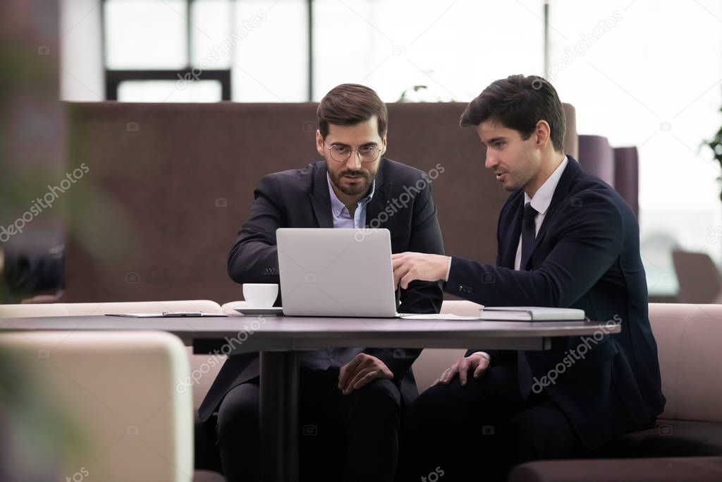 Focused employees in suits discussing corporate software.