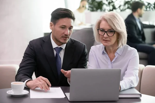 Fokussierter Geschäftsmann erklärt Finanzergebnisse der weiblichen Aufsichtskraft mittleren Alters. — Stockfoto