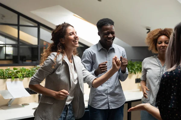 Overjoyed multiethnic colleagues have fun dancing in office — ストック写真