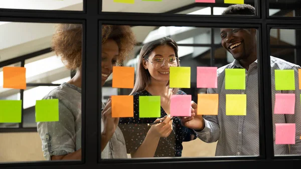 Equipe sorrindo multiétnico brainstorm usando notas pegajosas — Fotografia de Stock