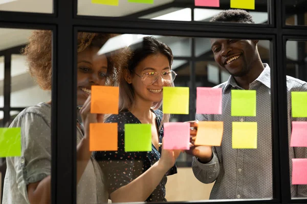 Glimlachende multiraciale collega 's ontwikkelen project over plakkerige notities — Stockfoto