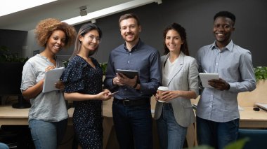 Ofiste poz veren gülümseyen çoklu etnik takımın grup portresi