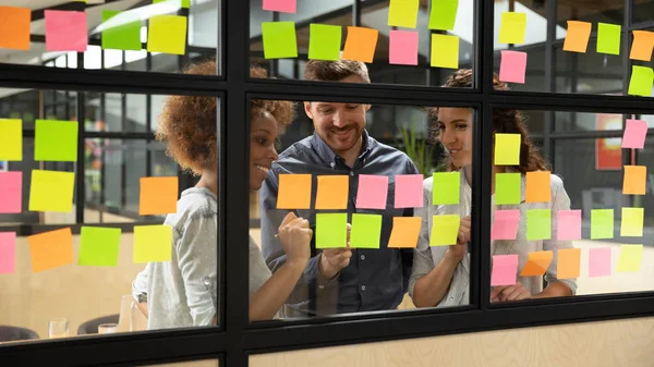 Sorrindo colegas multiétnicos brainstorm trabalhando com notas pegajosas — Fotografia de Stock