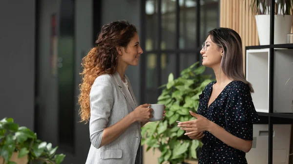 Multiethnic female colleagues chat during coffee break — Stock Photo, Image