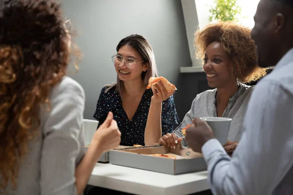 Overjoyed multiracial colleagues have fun enjoying pizza break in office — ストック写真