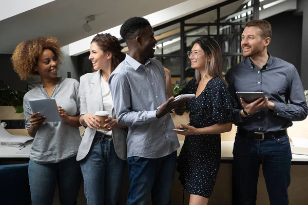 Overjoyed multiethnic employees stand laughing cooperating in office — Stock Photo, Image