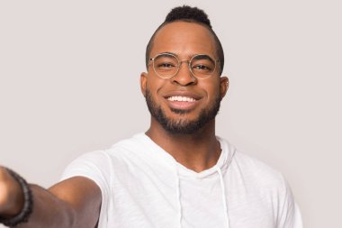 Gözlüklü gülümseyen siyah adam stüdyoda selfie çekiyor.