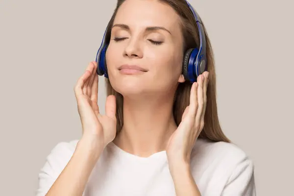 Расслабленная молодая женщина слушает музыку в наушниках — стоковое фото