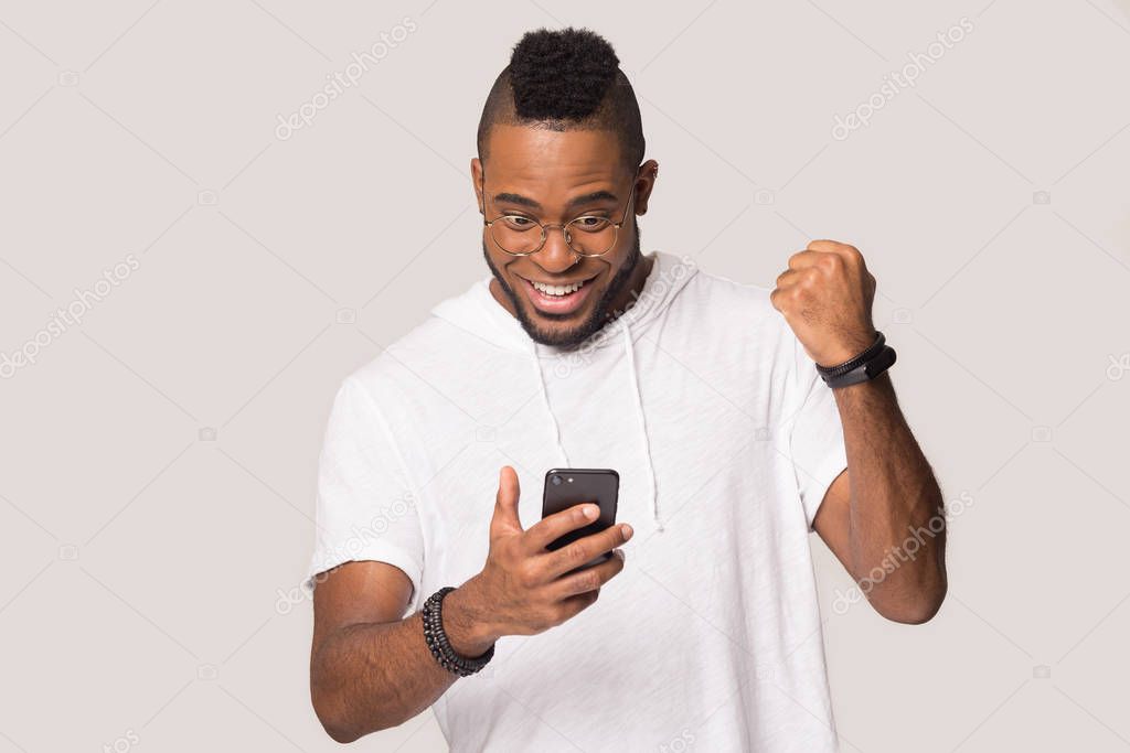 Happy african American man hold smartphone get good message