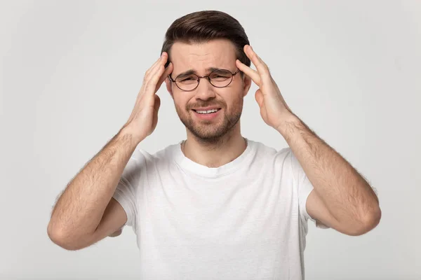 Moe millennial man masseren tempels, lijden aan plotselinge hoofdpijn. — Stockfoto