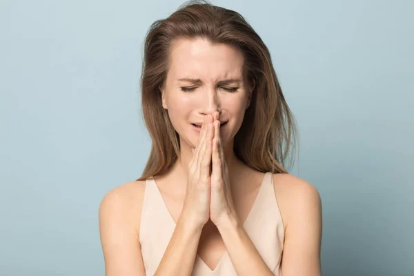 Депрессивная молодая женщина плачет, держа руки в молитве — стоковое фото